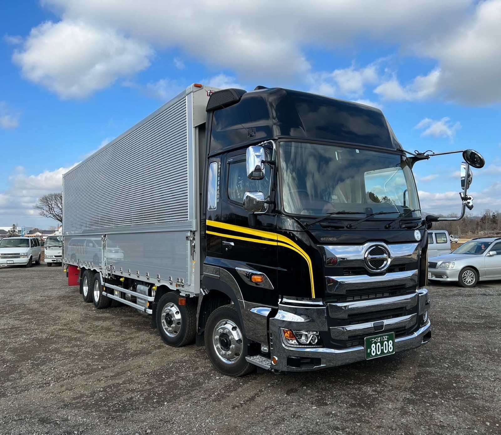 黒いキャブに金色のラインが入ったユウセイ商事の大型ウイング車
